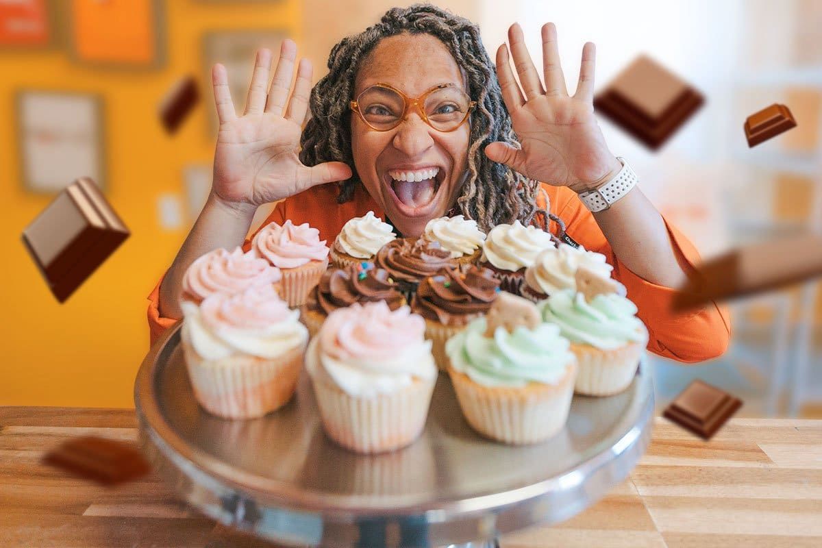 smiling woman with cupcakes on table